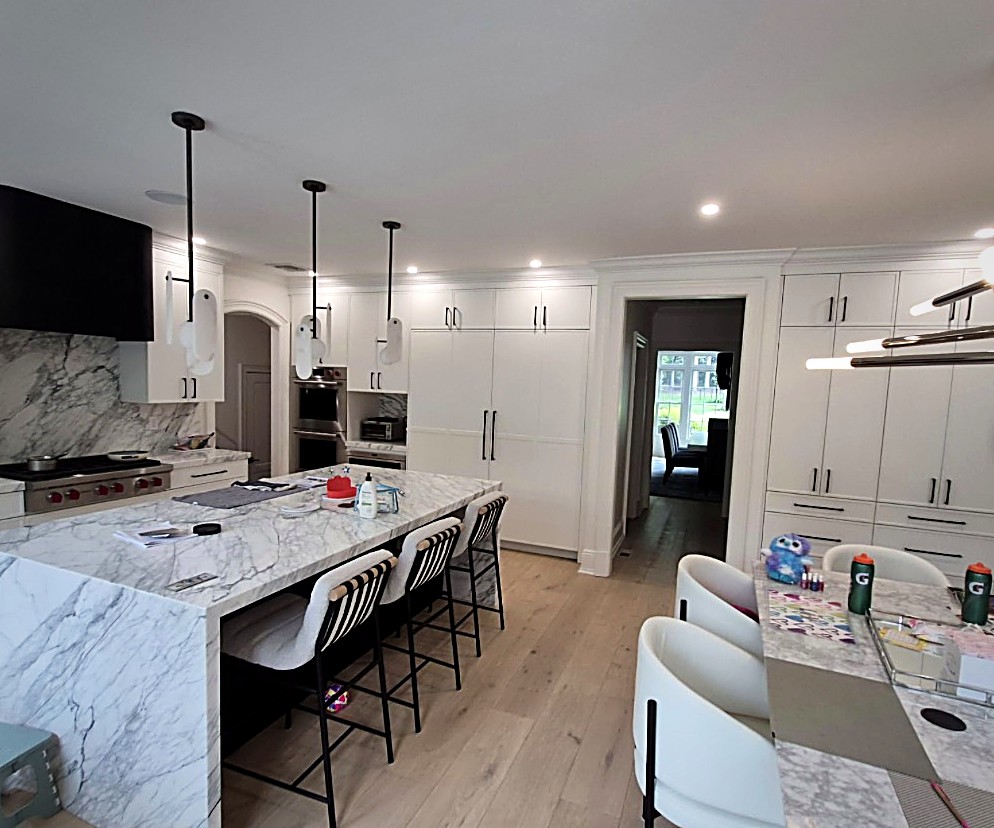 Finished Copperline kitchen with a book-matched marble waterfall island, white cabinetry and wide-plank floors