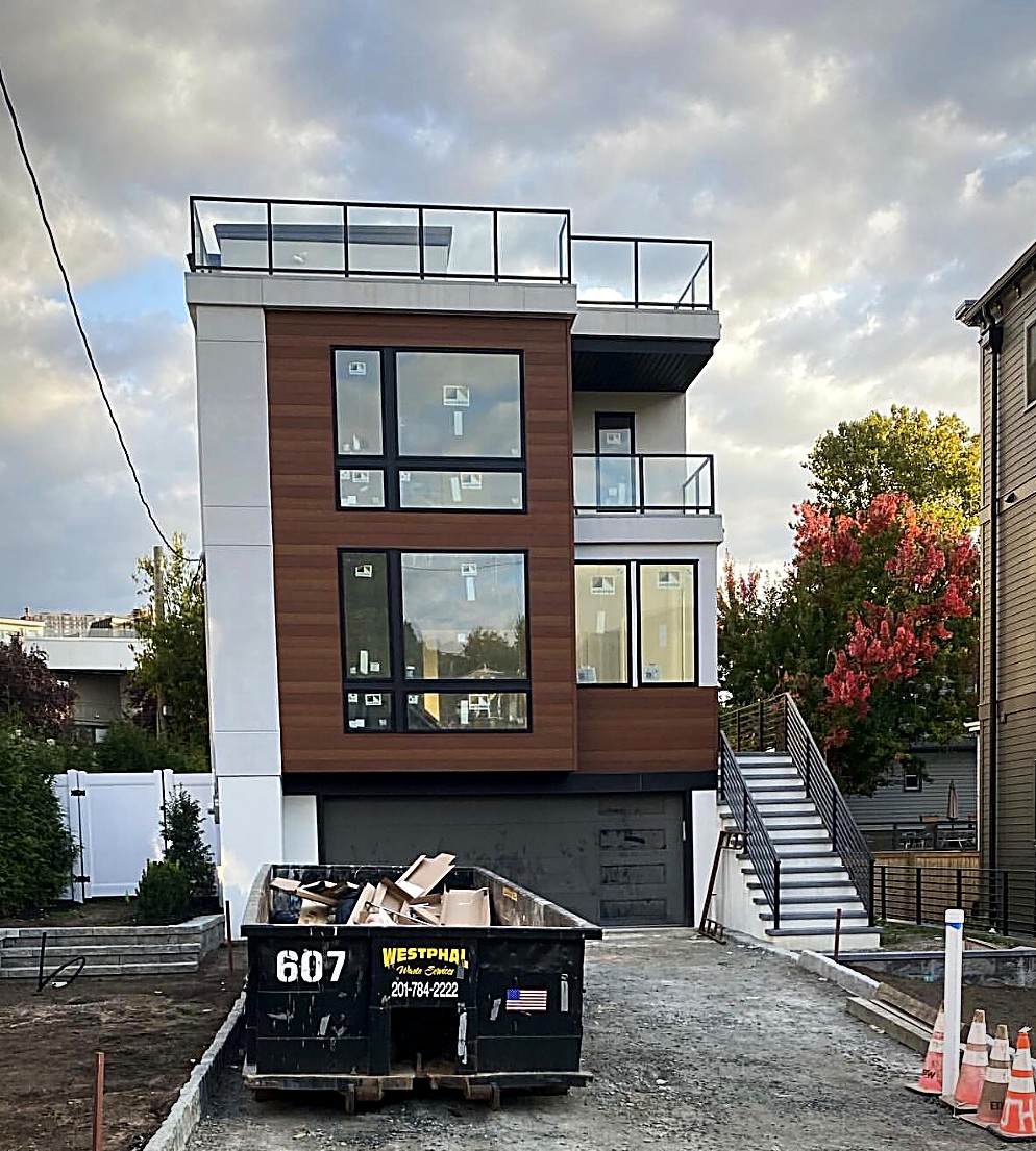 A completed modern Copperline home at dusk with a rooftop deck, wood clad façade and black framed glass