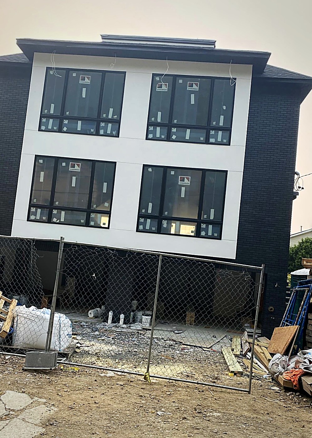 A Copperline modern home nearing completion, white stucco and black brick with large black framed windows